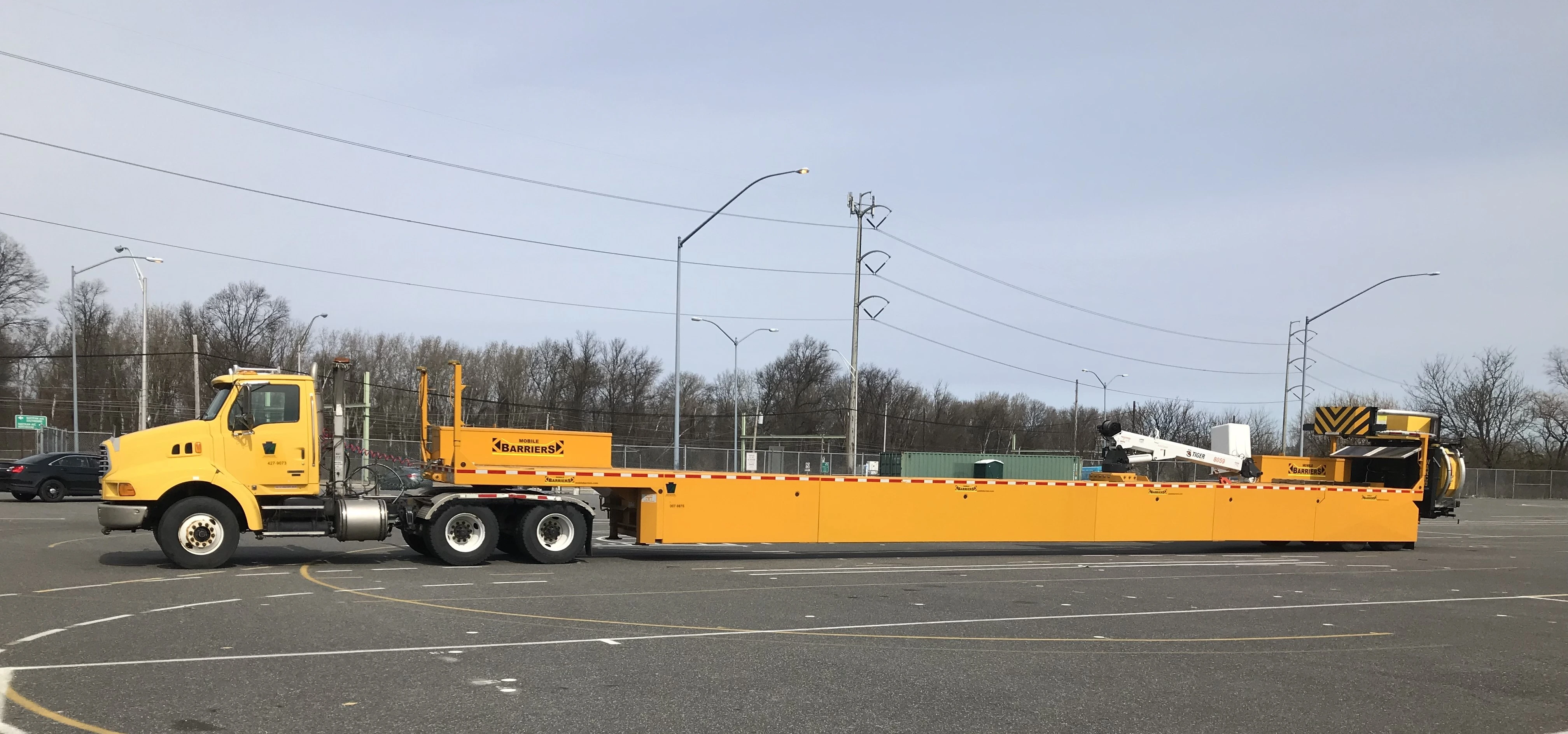 An image of a 110-foot-long yellow mobile truck barrier sitting in a parking lot.
